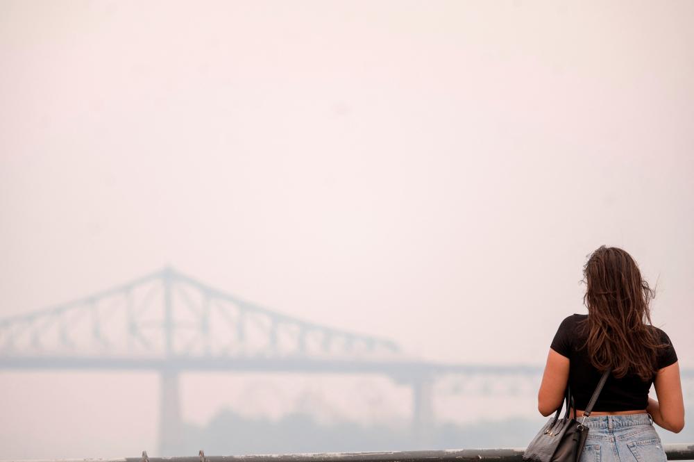 A woman looks at the Jacques-Cartier Bridge through the smoke caused by the wildfires in Northern Quebec in Montreal, Quebec, on June 25, 2023. AFPPIX