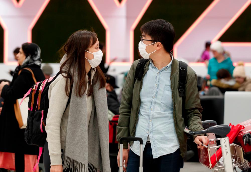 Travellers are seen wearing masks at the international arrivals area at the Toronto Pearson Airport in Toronto, Canada, Jan 26. — AFP