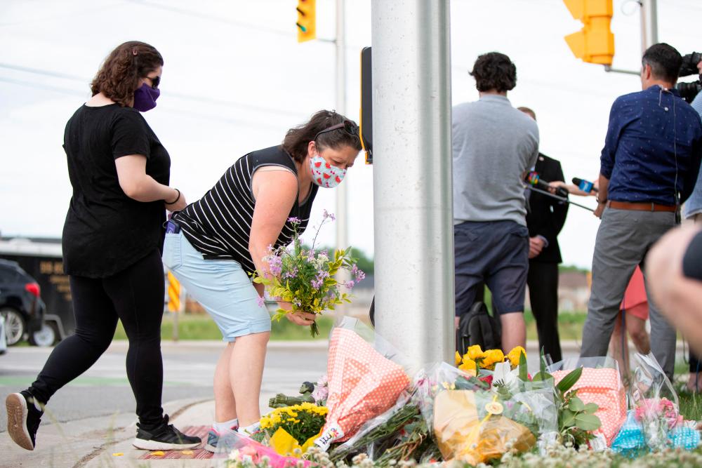 People pay their respects at the scene where a man driving a pickup truck struck and killed four members of a Muslim family in London, Ontario, Canada on June 7, 2021. A man driving a pick-up truck slammed into and killed four members of a Muslim family in the south of Canada's Ontario province, in what police said Monday was a premeditated attack. – AFP