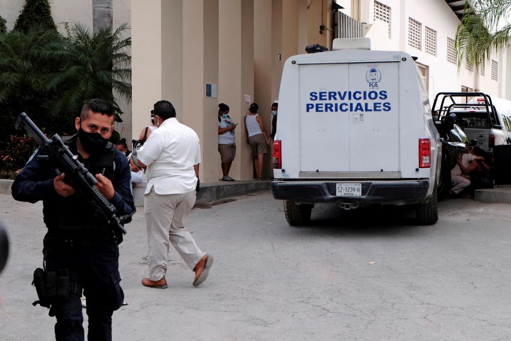 A police officer keeps watch as a vehicle from the coroner's office is parked at the entrance to a hotel after two suspected drug gang members were shot dead in a beachfront clash between rival groups near the Mexican resort of Cancun, in Puerto Morelos, Mexico November 4, 2021. REUTERSpix