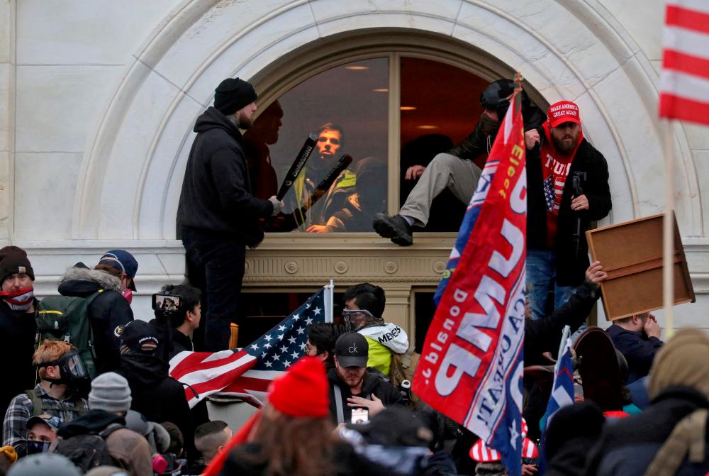 FILE PHOTO: A mob of supporters of then-U.S. President Donald Trump climb through a window they broke as they storm the U.S. Capitol Building in Washington, U.S., January 6, 2021. REUTERSpix