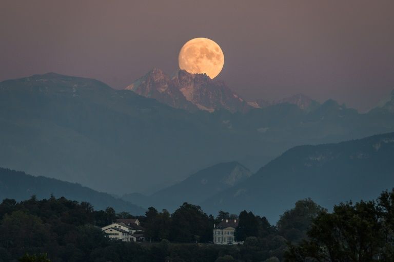 A near full moon rises behind The French Alps as seen from Geneva. — AFP