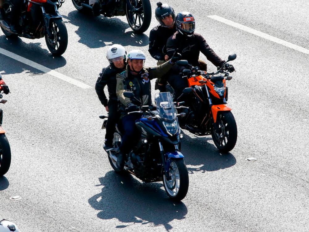 Brazilian President Jair Bolsonaro gestures to supporters as he leads a motorcycle rally in Sao Paulo on June 12, 2021. — AFP