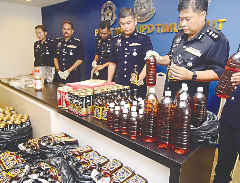 Che Zamani (right) and his officers showing some of the seized liquor during a press conference yesterday. — BBXPIX