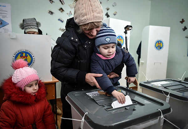 A woman enlists the help of a child to cast her vote at a polling station in Chisinau — AFP