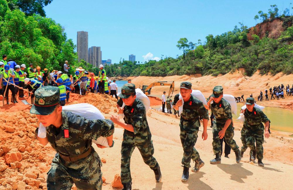 This photo taken on July 15, 2021 shows paramilitary police officers working on a flooded tunnel after 14 workers were trapped in Zhuhai, in China's southern Guangdong province. – AFP