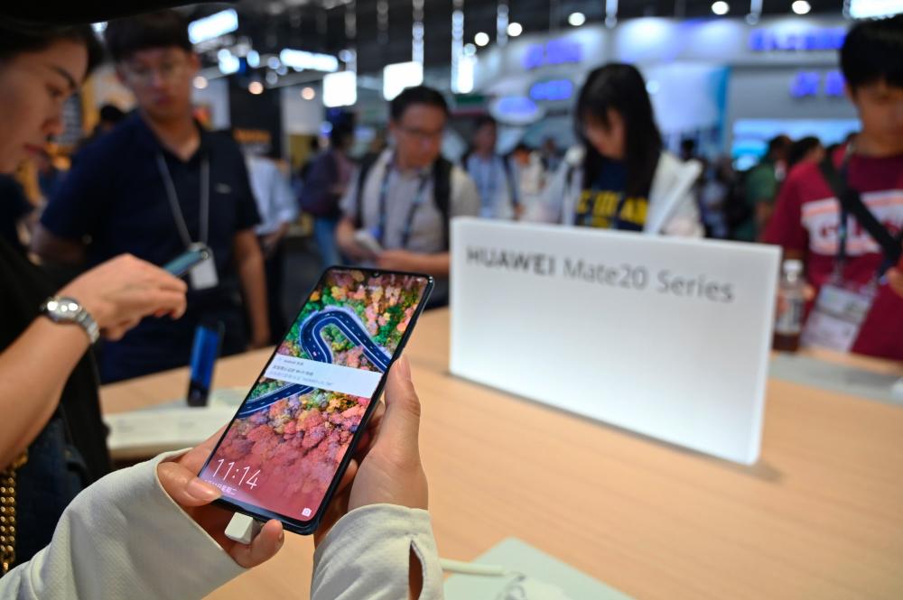 People look at the new Huawei smartphones at the company stand during the Consumer Electronics Show, Ces Asia 2019 in Shanghai on June 11, 2019. - AFP