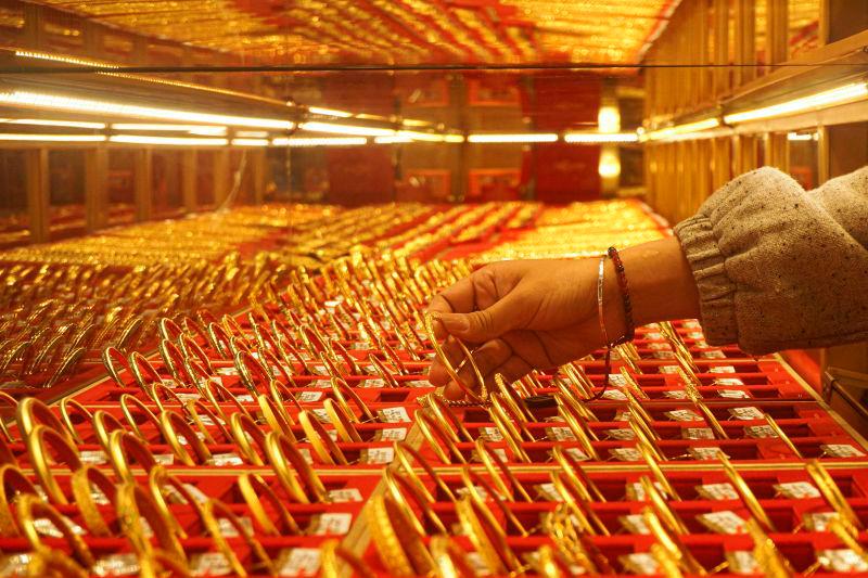 A shop assistant displays gold bangles for sale at a gold shop in Hangzhou, in eastern China’s Zhejiang province on April 22, 2025.