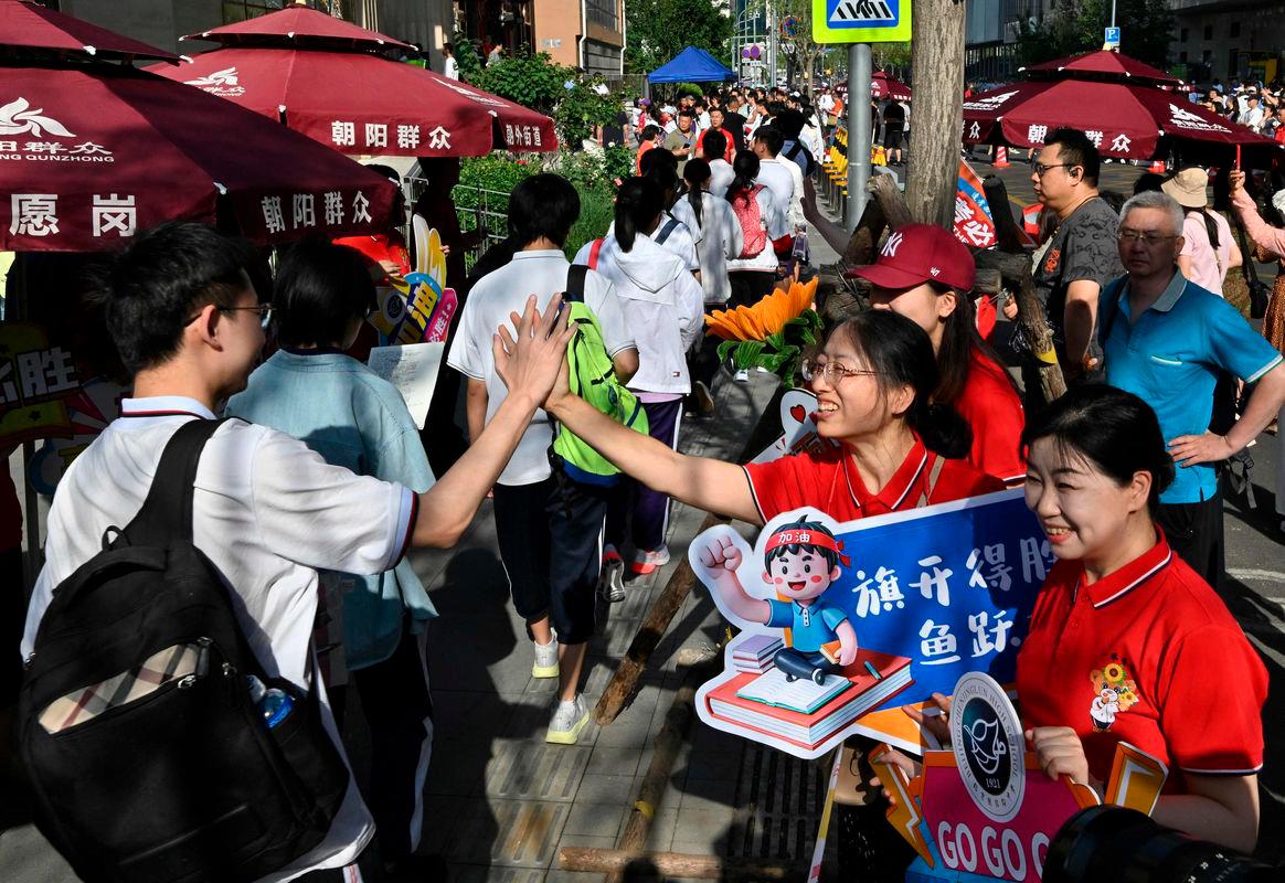 School staff members welcome students as they enter a school during China’s National College Entrance Examination (NCEE), known as “gaokao” - AFPPIX