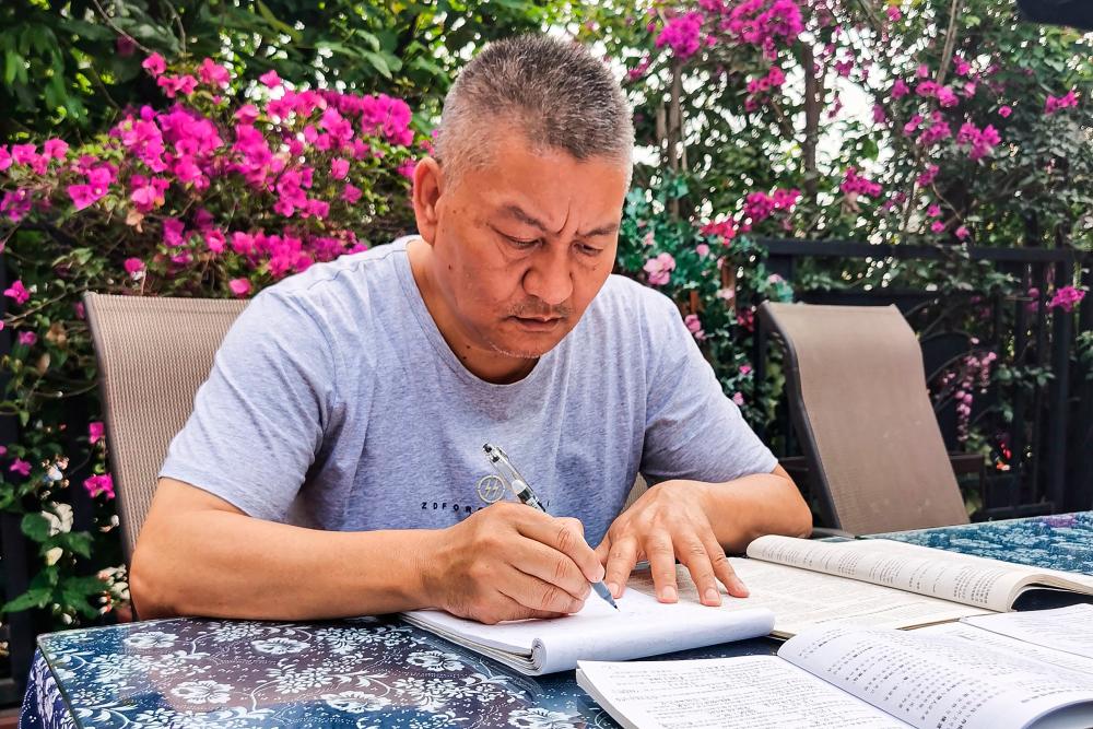 This handout picture taken on May 25 and released to AFP by Liang Shi on June 6, 2023 shows Liang Shi, a fifty-six-year-old man who sat Gaokao for the 27th time this year, going through exam papers ahead of the exam in Chengdu, in China’s southwestern Sichuan province. AFPPIX