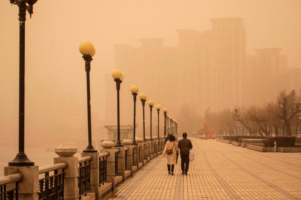People walk along a promenade next to the Songhua River during a sandstorm in Jilin, in China’s northeastern Jilin province on March 22, 2023. AFPPIX