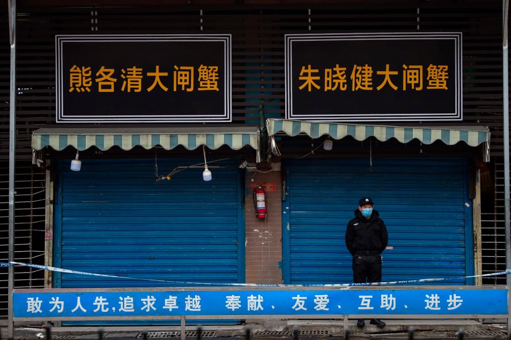 A security guard stands outside the Huanan Seafood Wholesale Market where the coronavirus was detected in Wuhan on Jan 24. — AFP