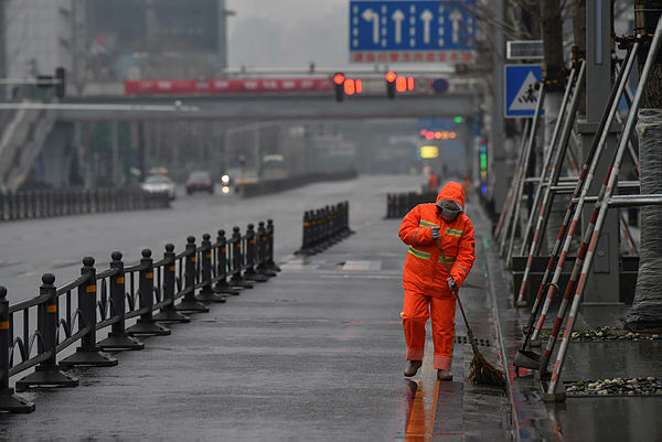 A worker wearing a protective facemask sweeps a street in Wuhan on January 25, 2020. — AFP