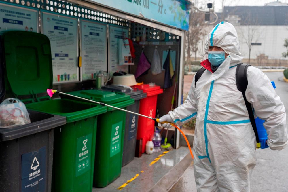 This photo taken on January 23, 2022 shows a staff member spraying disinfectant at a residental area as the city starts to reopen after a Covid-19 coronavirus lockdown in Xi’an in China’s northern Shaanxi province. AFPPIX