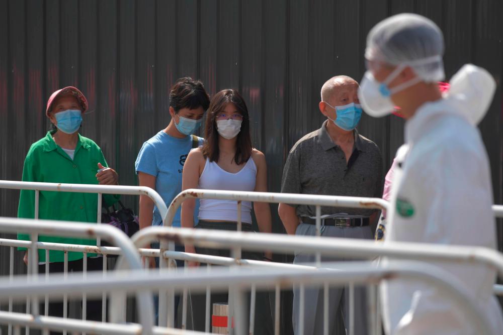 People wait in line to undergo Covid-19 coronavirus swab tests at a testing station in Beijing on June 30, 2020. China's capital has partially lifted a weeks-long lockdown imposed to head off a feared second wave of coronavirus infections after more than eight million samples have been taken. — AFP