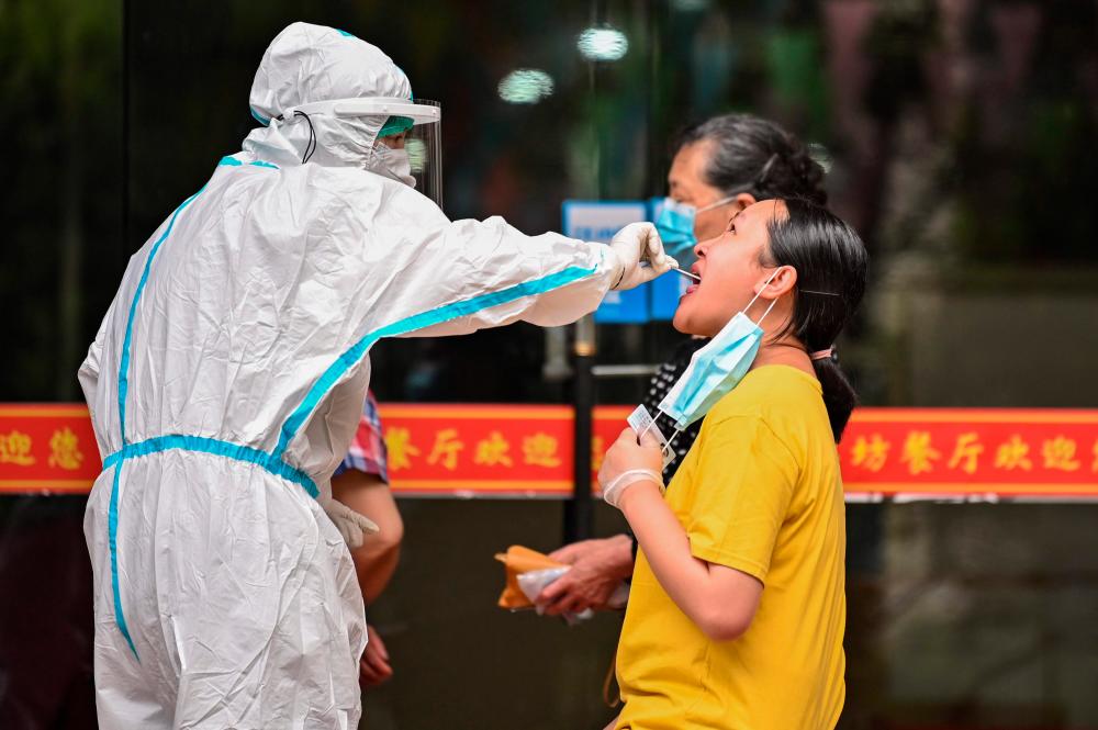 A medical worker takes a swab sample from a man to be tested for the Covid-19 coronavirus next to a street in Wuhan, in China’s central Hubei province on May 16, 2020. — AFP