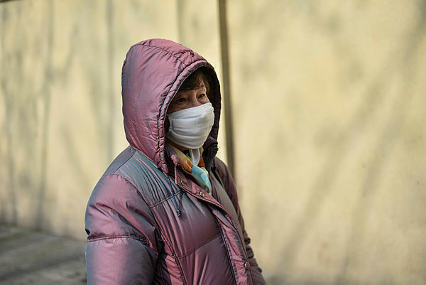 A woman wearing a protective mask stands are seen in front of the Huashan Hospital in Shanghai on Jan 21, 2020 — AFP