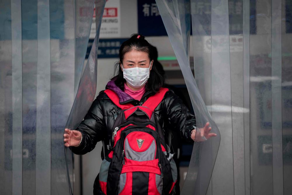 In this picture taken on Jan 27, a woman wearing a protective facemask to help stop the spread of a deadly virus which began in Wuhan, is seen at the Beijing railway station. — AFP