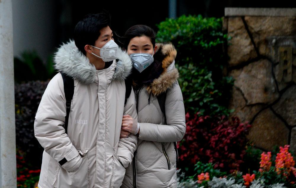 A couple wearing protective facemasks walks along a street in Shanghai on Feb 15, 2020. — AFP