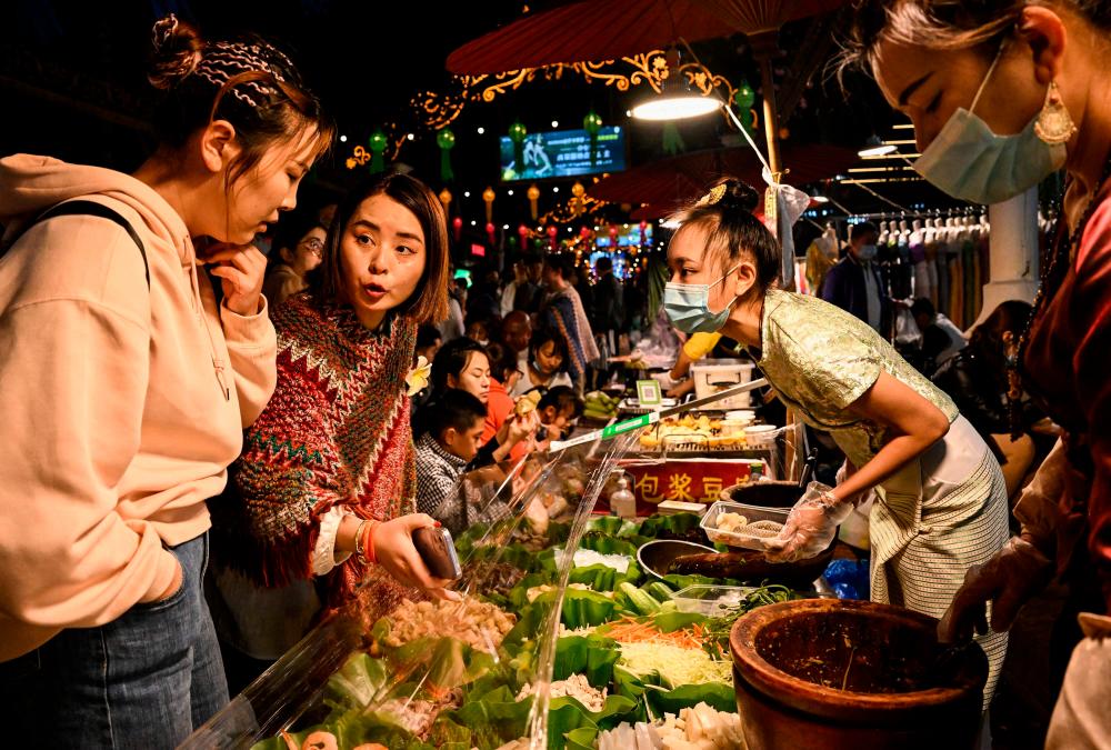 This photo taken on January 9, 2023, shows people at a night market at Jinghong City, at Xishuangbanna Dai Autonomous Prefecture, in China’s south Yunnan province. AFPPIX