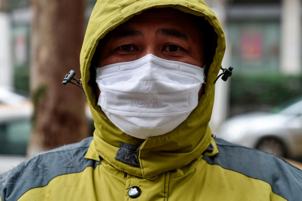 A man who works as a volunteer taking medicine for those who need it waits outside a pharmacy in Wuhan on Jan 26, a city at the epicentre of a viral outbreak. — AFP