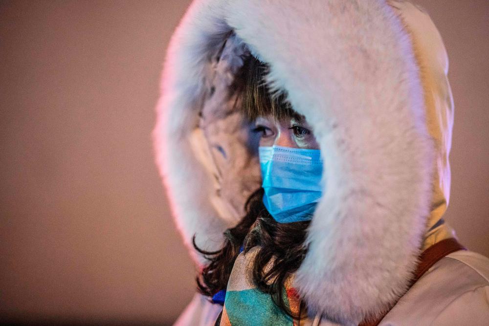 A woman wearing a protective mask looks on as she walks outside Beijing railway station in Beijing on Jan 22. — AFP