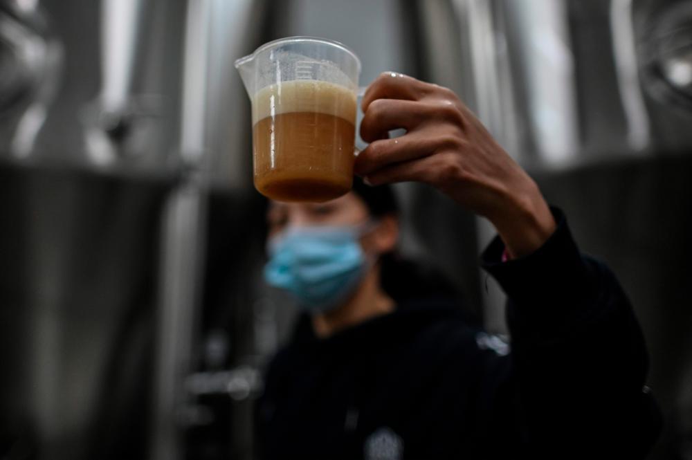 $!This photo taken on November 21, 2020 shows a worker taking a sample of beer at No. 18 Brewery in Wuhan, China’s central Hubei province. AFP / Hector RETAMAL