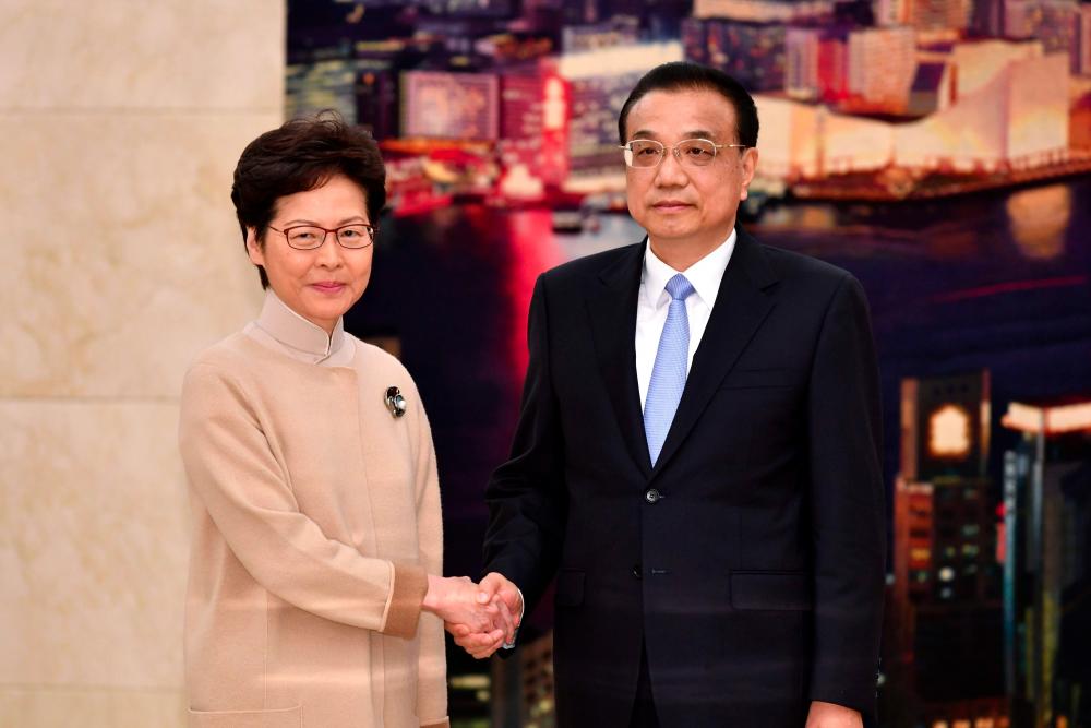 This handout photograph taken and released by the Hong Kong Government on Dec 16, shows Chinese Premier Li Keqiang (R) meeting with Hong Kong Chief Executive Carrie Lam during her annual duty visit, in Hong Kong Hall at the Great Hall of the People in Beijing. — AFP