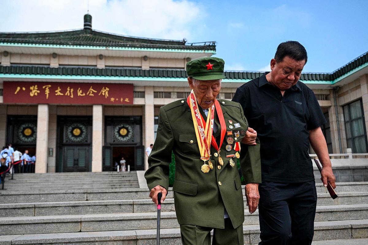This photo taken on July 23, 2025 shows Li Jinshui (L), a veteran of the Second Sino-Japanese War, walking after an interview with the media at the Eighth Route Army Taihang Memorial Hall in Wuxiang, in China’s northern Shanxi province. - HECTOR RETAMAL / AFP