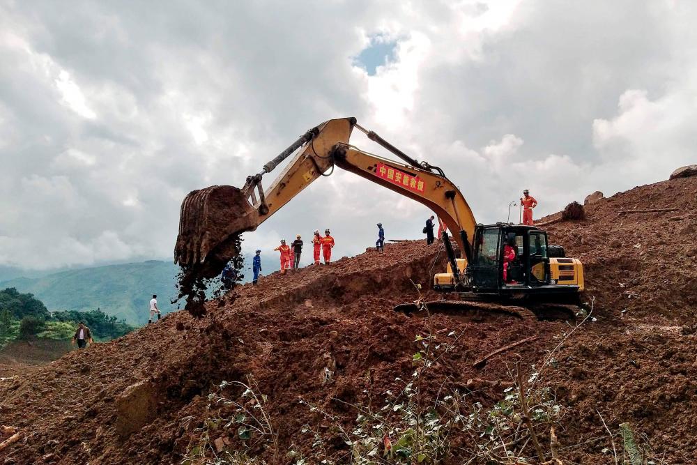 An excavator and rescuers work at the site of a landslide in Liupanshui in China's southwestern Guizhou province on July 24, 2019. Eleven people have died and 42 are missing after heavy rains triggered a landslide in southwest China's Guizhou province, the government said on July 24. — AFP