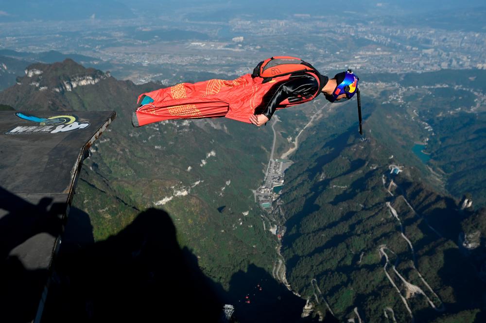 $!This picture taken on November 12, 2020 shows Zhang Shupeng in flight during a wingsuit jump from Tianmen mountain in Zhangjiajie, China’s Hunan province. Zhang Shupeng appears untroubled as he surveys the jagged mountains of a national park in central China -- before diving head-first off a cliff to bullet down at 230 kilometres (140 miles) an hour. -AFP / WANG ZHAO