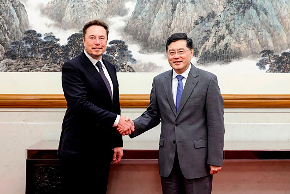 This handout picture taken and released by the Ministry of Foreign Affairs of the People’s Republic of China on May 30, 2023 shows Tesla CEO Elon Musk (L) shaking hands with China’s Foreign Minister Qin Gang during a meeting in Beijing/AFPPix