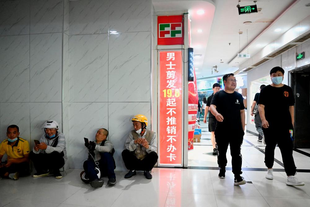This photo taken on August 17, 2022 shows food delivery workers (L) resting at a food court in Beijing’s middle-class neighbourhood of Shangdi. It is 10 years since Xi unveiled the “Chinese Dream”, a grand vision to restore the country’s global influence through a collective struggle for prosperity, power and glory, steered by the Chinese Communist Party. AFPPIX