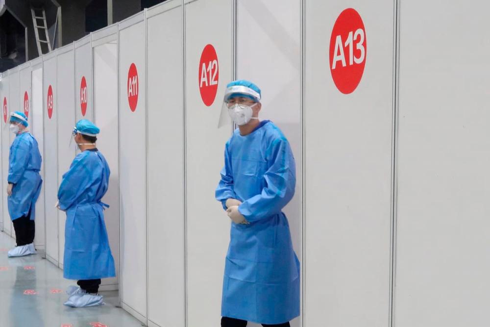 Staff members wait outside booths where people receive a vaccine against the coronavirus disease (Covid-19) at a vaccination center, during a government-organized visit, in Beijing, China, April 15, 2021. REUTERSpix