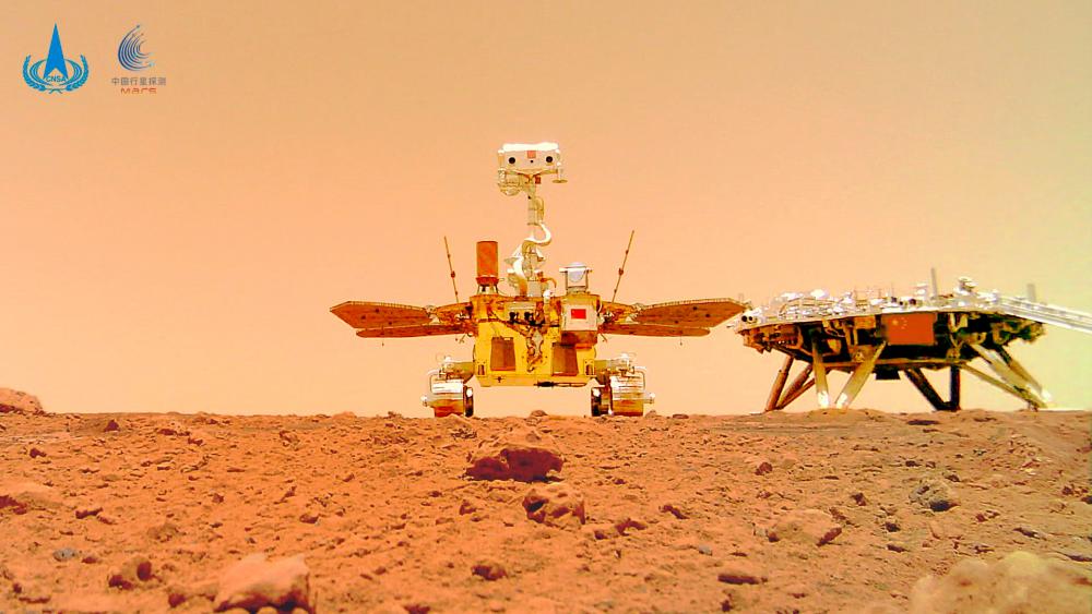 This undated handout photograph released on June 11, 2021 by the China National Space Administration (CNSA) shows an image taken by a camera released from China's Zhurong Mars rover showing the rover (L) and the landing platform on the surface of Mars. -----EDITORS NOTE --- RESTRICTED TO EDITORIAL USE - MANDATORY CREDIT AFP PHOTO / CNSA - NO MARKETING - NO ADVERTISING CAMPAIGNS - DISTRIBUTED AS A SERVICE TO CLIENTS / AFP / China National Space Administration (CNSA) / HANDOUT / -----EDITORS NOTE --- RESTRICTED TO EDITORIAL USE - MANDATORY CREDIT AFP PHOTO / CNSA - NO MARKETING - NO ADVERTISING CAMPAIGNS - DISTRIBUTED AS A SERVICE TO CLIENTS