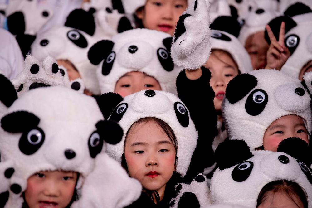 Children wearing a panda costume group together during the official reveal of the mascots for the Beijing 2022 Winter Olympic and Paralympic Games at Shougang Ice Hockey Arena, Shougang Park, Shijingshan District, Beijing in September 17, 2019. — AFP