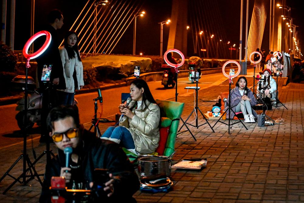 The photo taken on February 20, 2023 shows outdoor livestreamers singing and chatting with the audiences through their mobile phones on an overpass bridge at night in Guilin, in southern China’s Guangxi province. In the dead of night on a bridge in southern China, around two dozen livestreamers sat crooning and chatting into microphones, their identical ring lights spaced a few metres apart in glowing rows. AFPPIX
