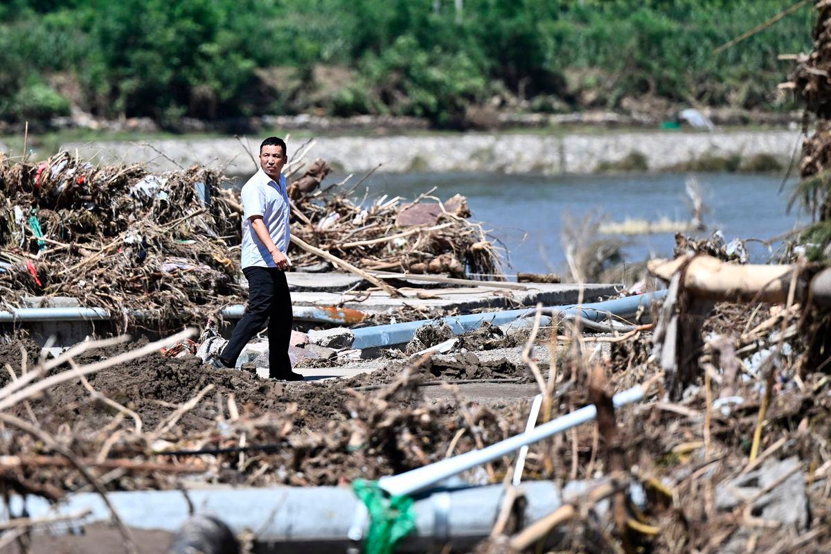 A man walks past a rain damaged area from the past few days in Huairou district, on the outskirts of Beijing on July 30, 2025. (Photo by Pedro Pardo / AFP)