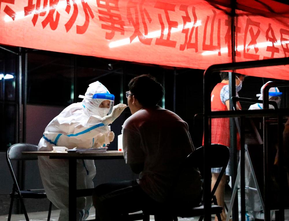 A medical worker in protective suit collects a swab from a resident for nucleic acid testing following new cases of the coronavirus disease (Covid-19) in Zhengzhou, Henan province, China early August 2, 2021. -Reuters