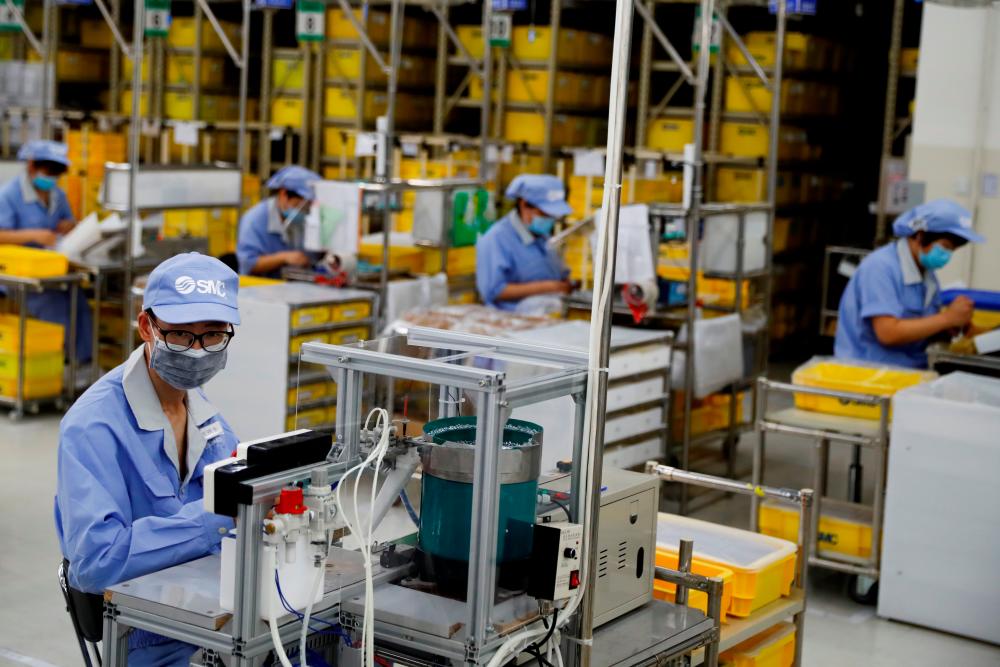 Workers in a factory of component maker SMC in Beijing, China. The OECD expects China to account for one-third of global growth next year. – REUTERSPIX