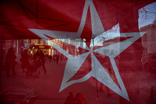 Passers-by are seen through a red banner bearing the Socialist Party’s star symbol in Chisinau — AFP