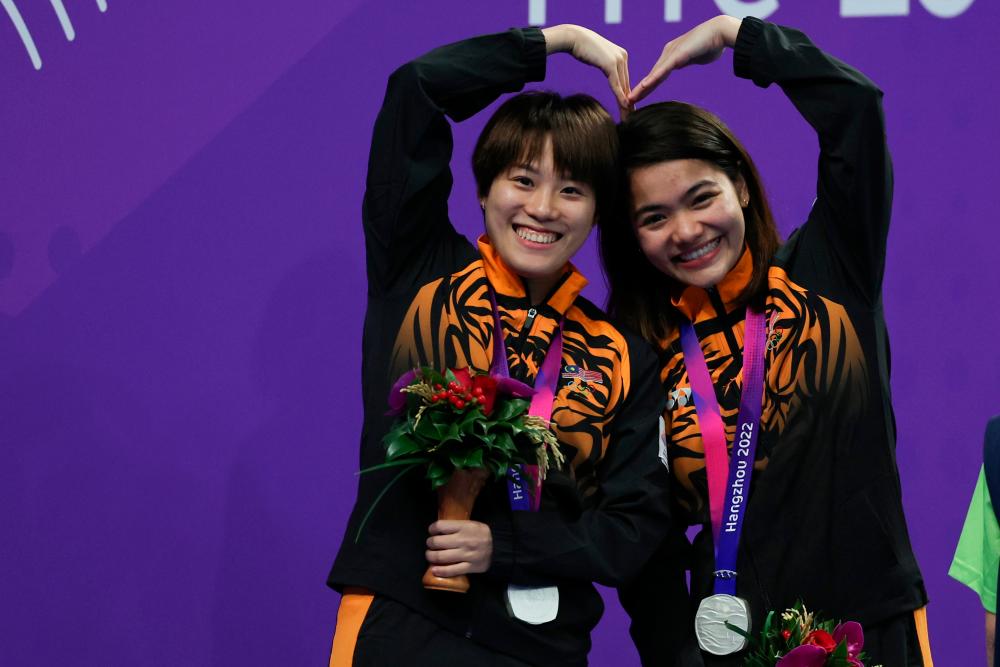 HANGZHOU, 1 Okt Sept -- Atlet terjun negara Nur Dhabitah Sabri dan Wendy Ng bergambar selepas meraih pingat perak dalam acara 3 Meter (M) papan anjal seirama wanita pada Sukan Asian Hangzhou 2022 di Arena Sukan Akuatik Pusat Sukan Olimpik Hangzhou semalam. fotoBERNAMA