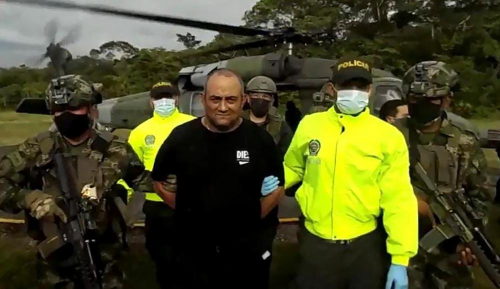 Handout video grab released on October 23, 2021 by the Colombian Army press office showing members of the Colombian Army and police escorting Colombia’s most-wanted drug lord and head of the Gulf Clan, Dairo Antonio Usuga (C) -alias ‘Otoniel’- after his capture, in Bogota. AFPpix