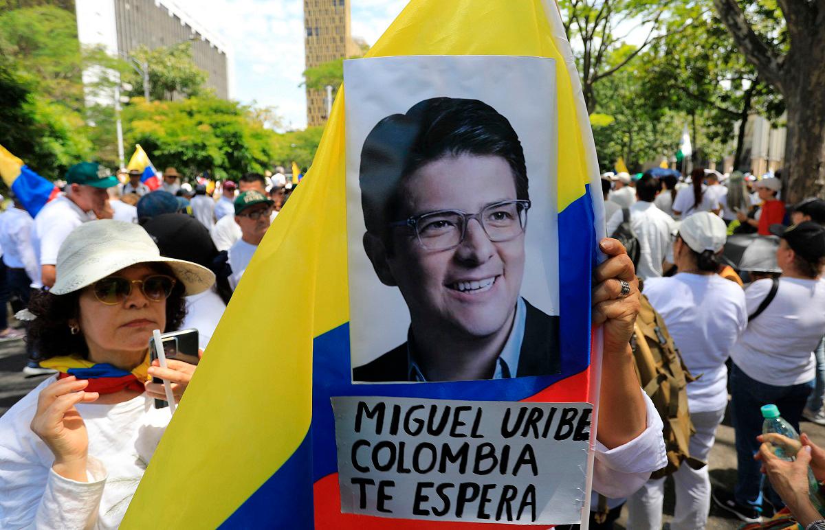 A woman holds a national flag during the so-called “Silent March” to show support for the health of Senator Miguel Uribe Turbay and to call for peace for the country in Medellin, Colombia, on June 15, 2025. Uribe, a 39-year-old conservative senator, was shot twice in the head and once in the leg while giving a speech in a park on June 7 in western Bogota. - JAIME SALDARRIAGA / AFP