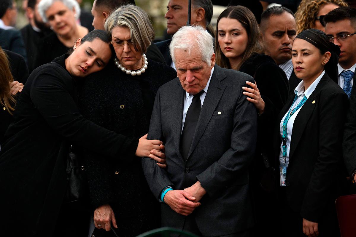 Miguel Uribe Londono (C), father of slain Colombian presidential candidate Miguel Uribe, looks at the coffin of his son during the burial at the Central Cemetery in Bogota on August 13, 2025. - Raul ARBOLEDA / AFP