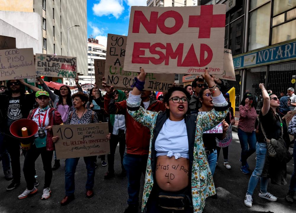 People hold signs during a protest against Colombian President Ivan Duque at the Bolivar square in Bogota, on Dec 4, 2019. — AFP