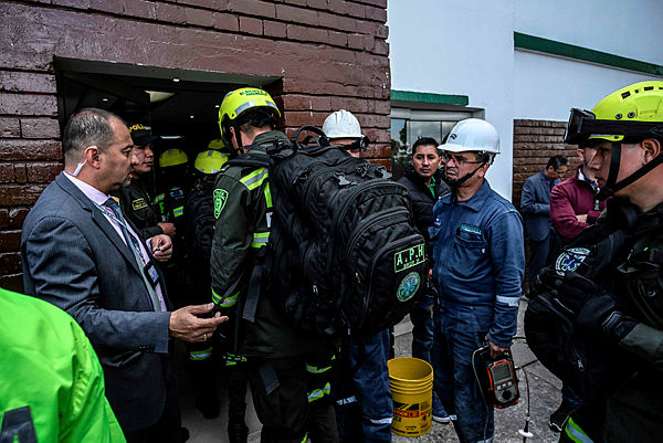 Firefighters work at the scene of a car bomb attack in a police academy in Bogota that left at least nine people dead and 54 injured. — AFP