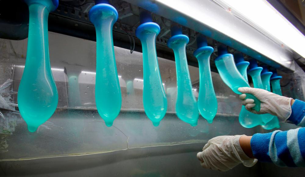 Filepix of a worker performing a test on condoms at Malaysia's Karex condom factory in Pontian. — Reuters