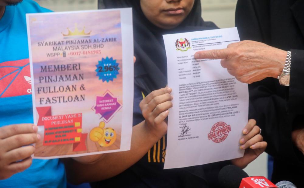The victim, showing the loan scam scheme advertisement, at a press conference, on July 2, 2019. — Sunpix by Amirul Syafiq Mohd Din