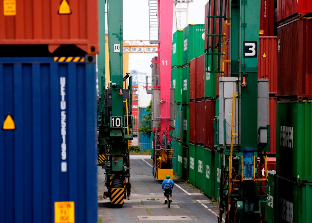FILE PHOTO: A man in a bicycle drives past containers at an industrial port in Tokyo, Japan, May 22, 2019. REUTERS/Kim Kyung-Hoon/File Photo